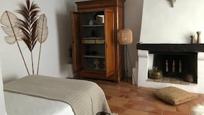 Un dormitorio con cama, un armario de madera, una chimenea y decoración en la pared.