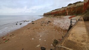 A beach with a rocky shoreline and a cliff with red and white layers. - Harvey's Holiday House (Hunstanton)