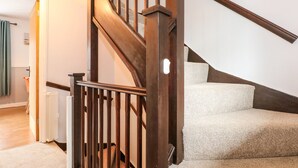 A wooden staircase with a handrail, carpeted steps, and a white door leading to another room. - Harvey's Holiday House (Hunstanton)