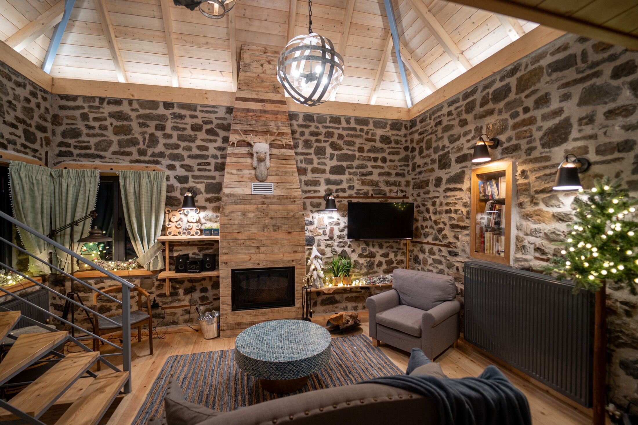 Um quarto acolhedor com parede de pedra, lareira, sofá e televisão.