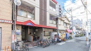 Vista de una calle con un edificio que tiene un toldo rojo y un letrero que dice 'Air Cafe'. Hay bicicletas estacionadas frente al edificio.