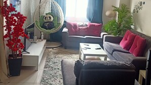 Un salon avec un fauteuil suspendu, un canapé, une table basse et une plante en pot.
