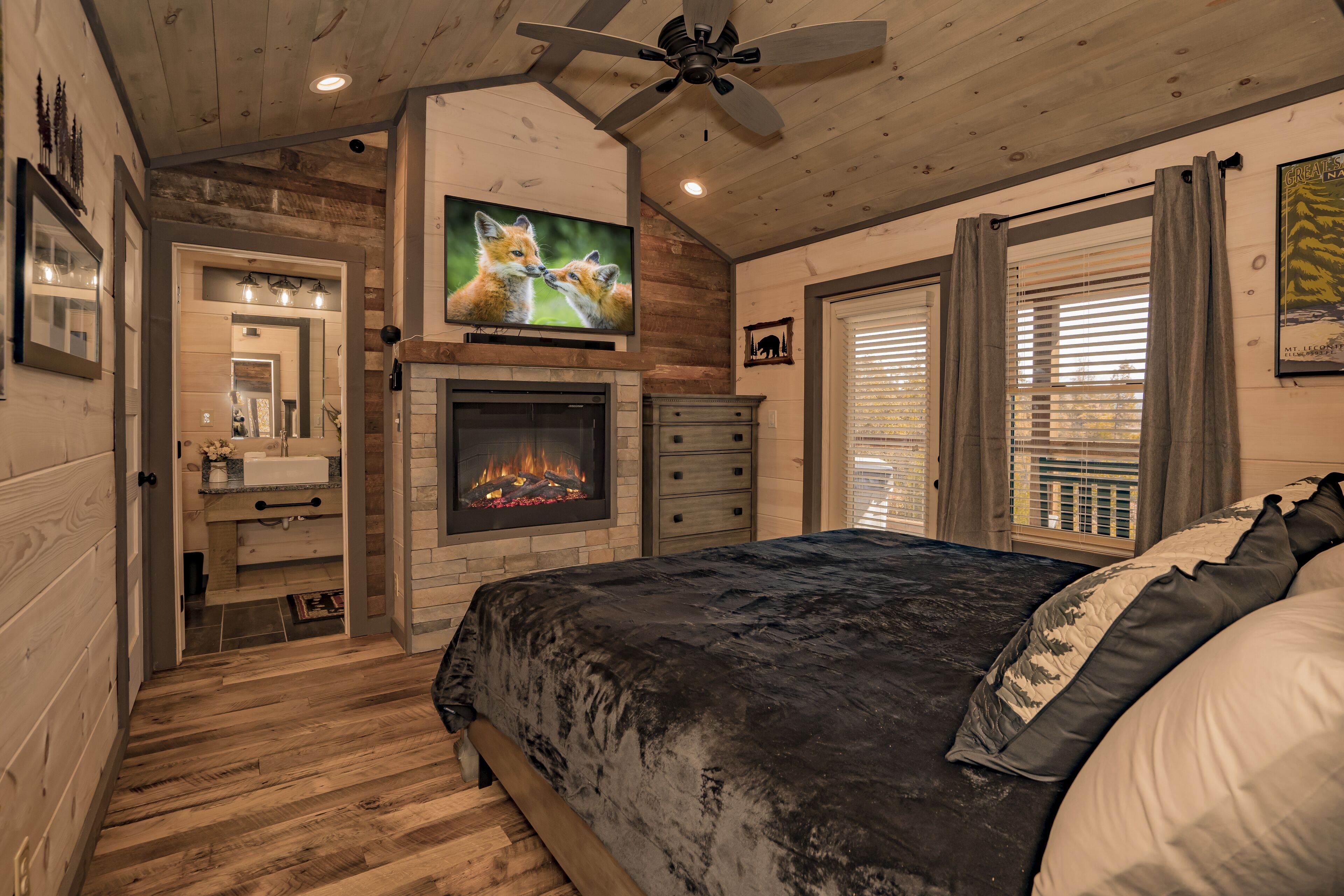 A bedroom with a fireplace, a television, and a large bed.