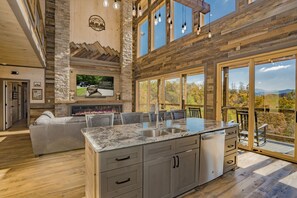A spacious kitchen with a large island, built-in appliances, and a stone accent wall.