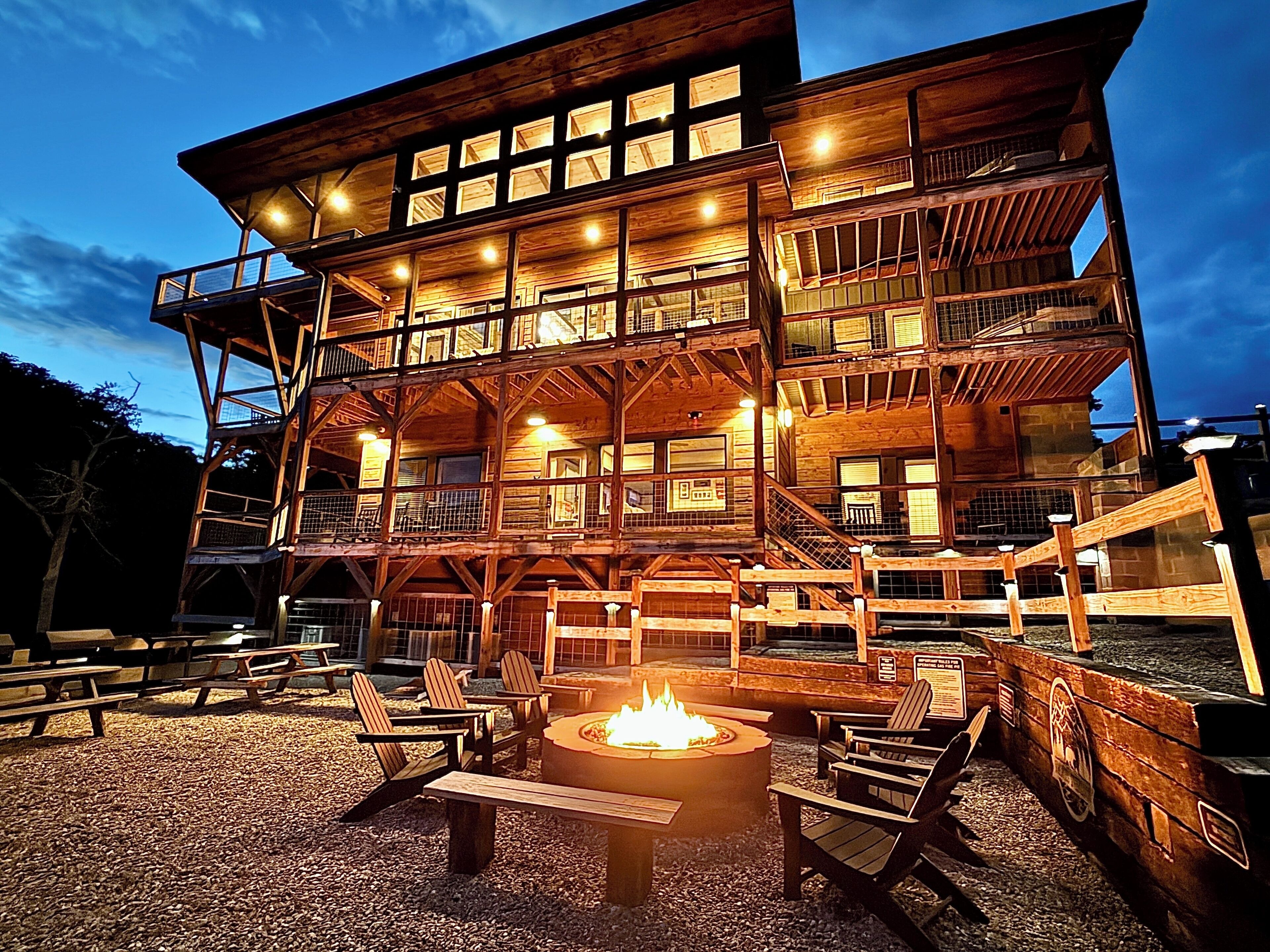 A multi-story wooden cabin with outdoor seating and a fire pit.