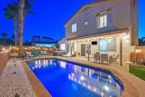 A swimming pool with lounge chairs and a patio area, surrounded by a house with a covered outdoor kitchen. - Henderson 4BR Home • Pool & Hot Tub • Sleeps 10 (Henderson)
