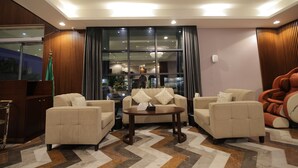 A modern hotel lobby with a sofa set, a coffee table, and a massage chair. - Laten Suites Al Salim Plaza (Jeddah)