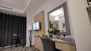 A hotel room with a desk, chair, TV, and a mirror. - Laten Suites Al Salim Plaza (Jeddah)