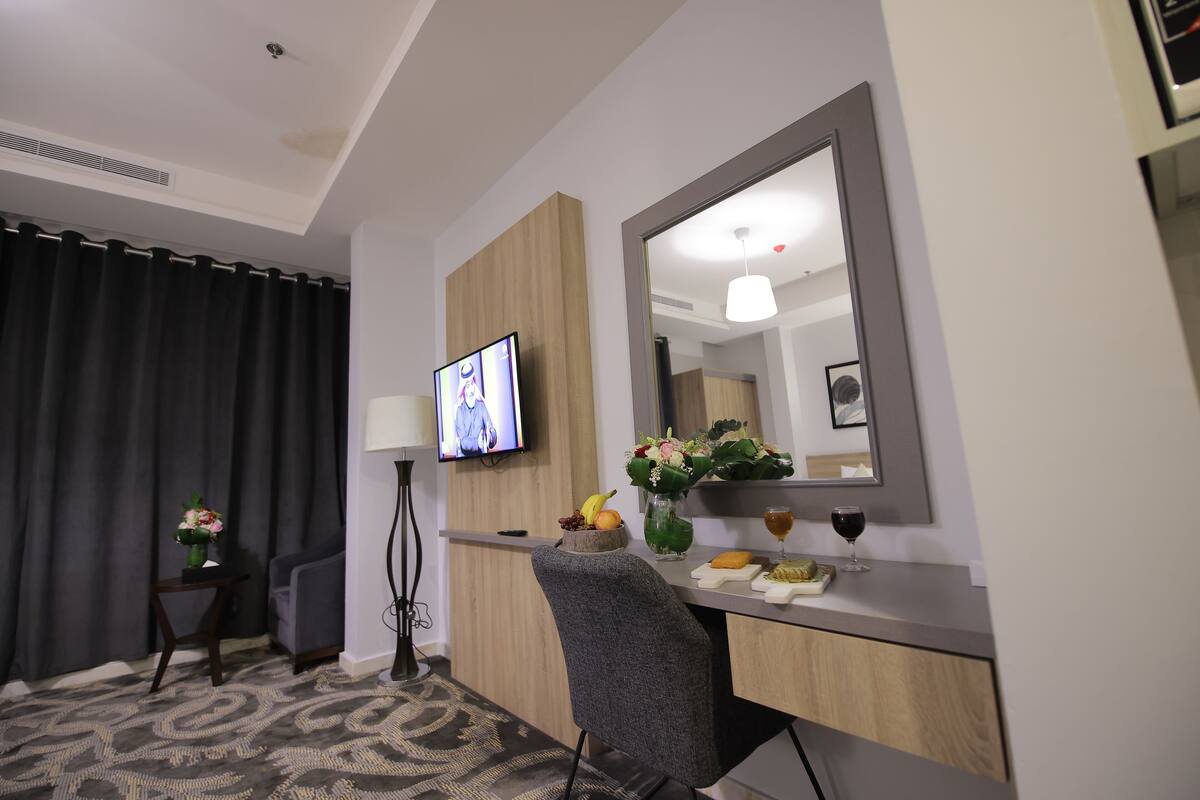 Une chambre d’hôtel équipée d’un bureau, d’une chaise, d’une télévision et d’un miroir.