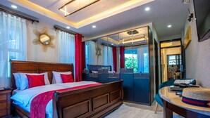A bedroom with a wooden bed, a vanity with a mirror, and a view of the outdoors.