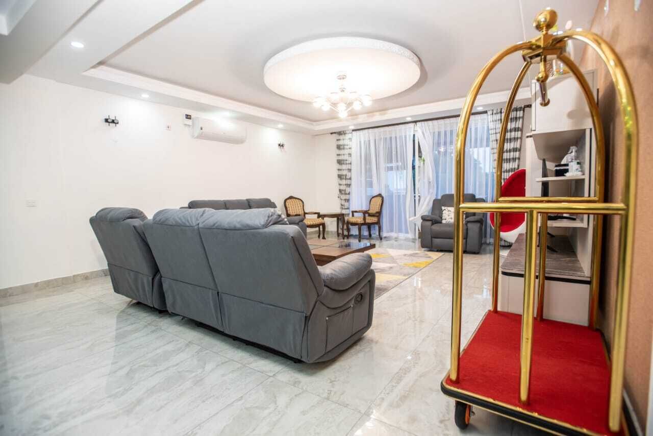 Ein modernes Wohnzimmer mit einem grauen Sofa, einem kleinen Esstisch und einem Stuhl in Rot und Gold.