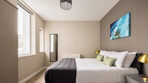 A bedroom with a bed, bedside table, lamp, and a painting on the wall.
