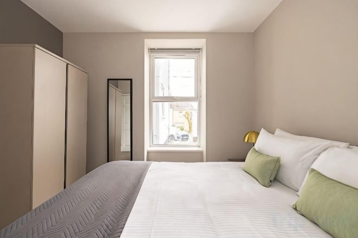 A bedroom with a bed, a wardrobe, a mirror, and a window.