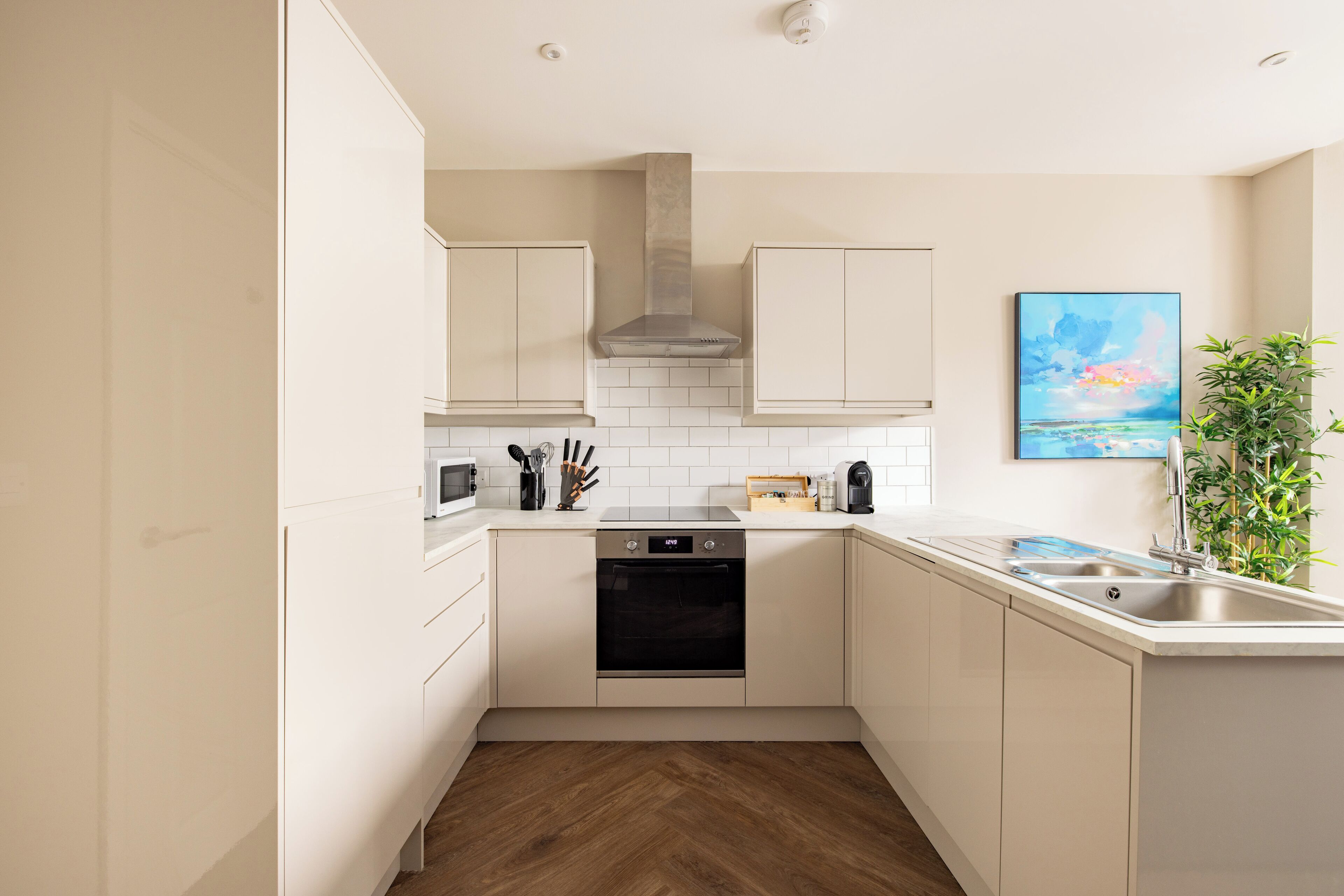 A modern kitchen with white cabinets, a built-in oven, and a sink.