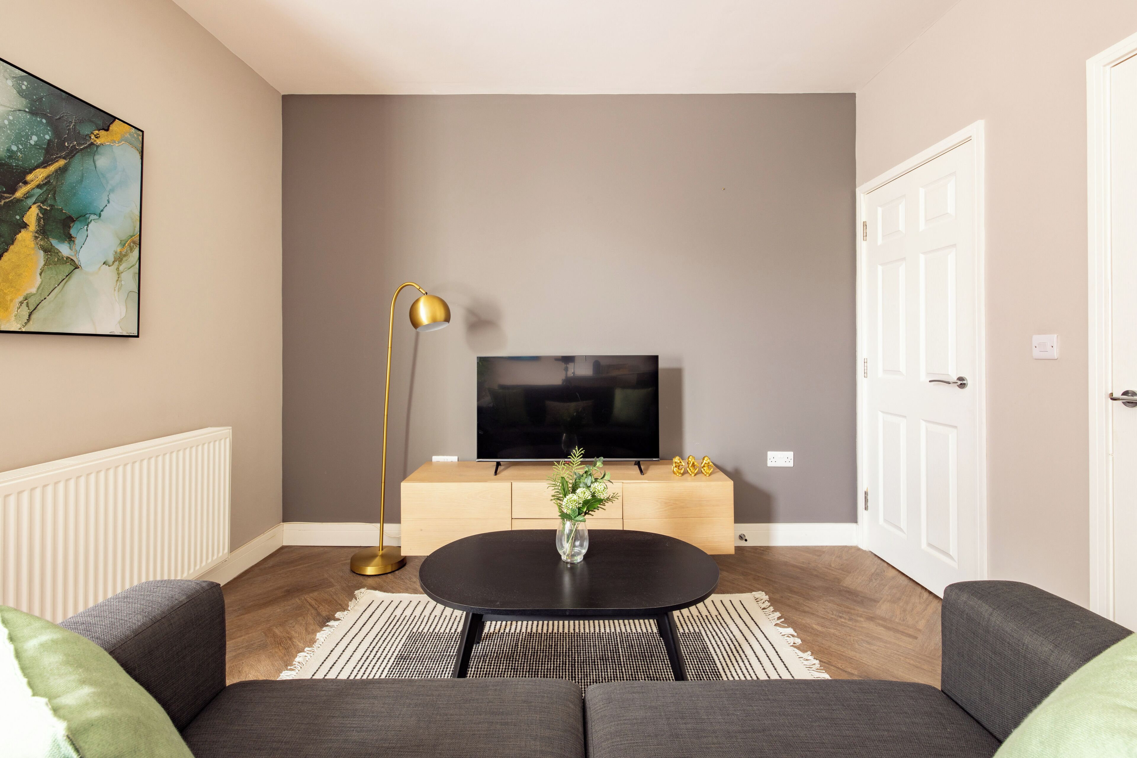 Una sala de estar moderna con un sofá, una mesa de centro, un televisor y un jarrón decorativo.
