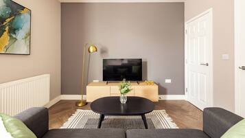 Un soggiorno moderno con un divano, un tavolino, una TV e un vaso decorativo.