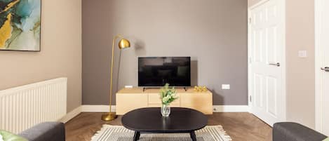 A modern living room with a sofa, a coffee table, a TV, and a decorative vase.