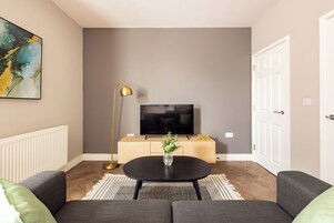 A modern living room with a sofa, a coffee table, a TV, and a decorative vase.