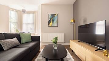 A modern living room with a sofa, a coffee table, a TV, and a radiator.