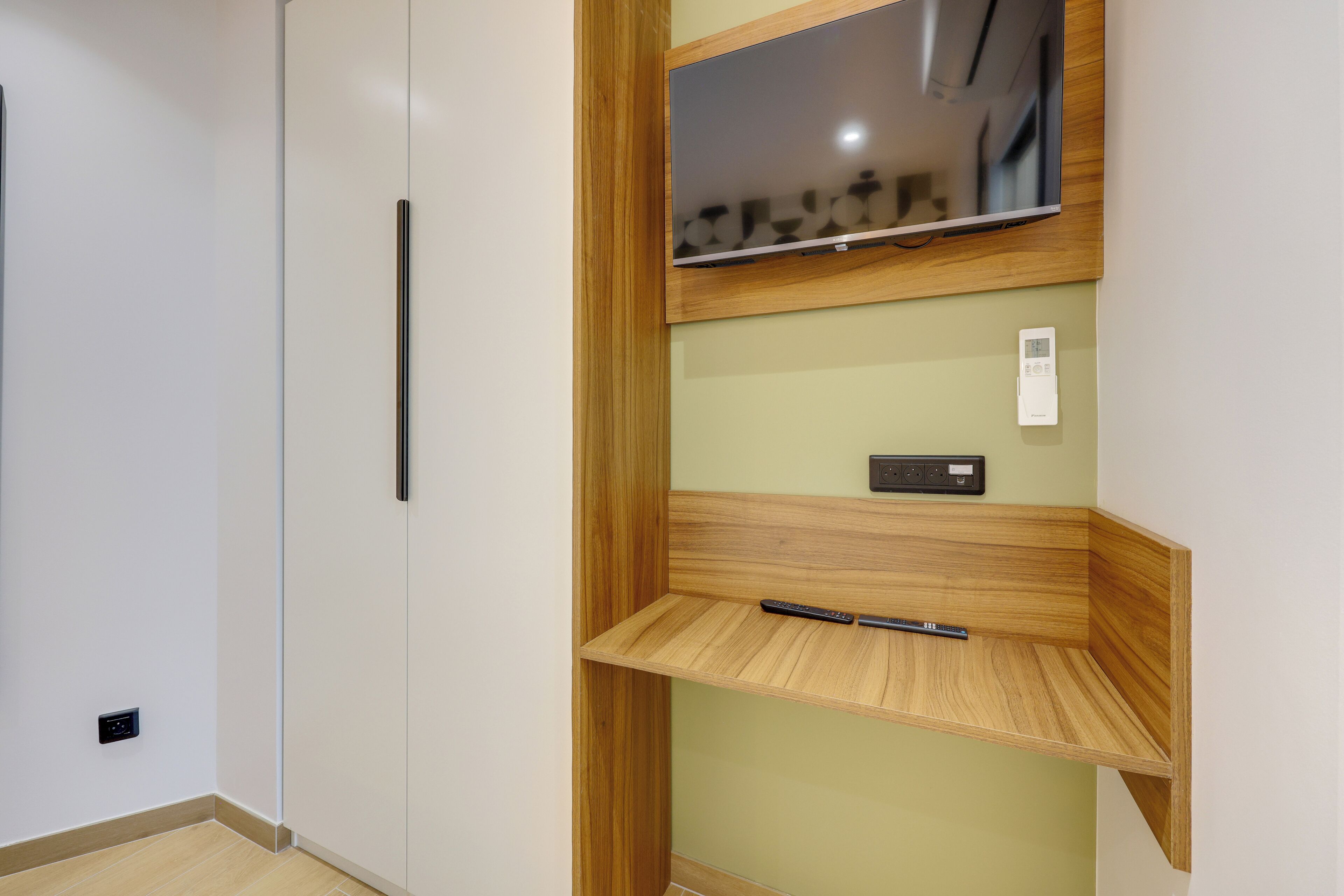 Een kamer met een ingebouwde tv-plank, een thermostaat en een afstandsbediening op een houten plank.