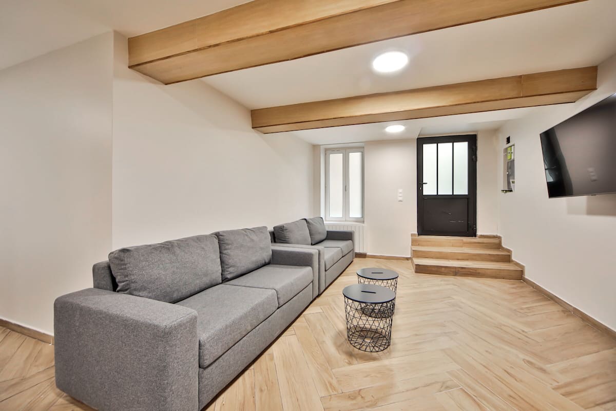A modern living room with a grey sectional sofa, a small round side table, and a staircase leading to an upper level.