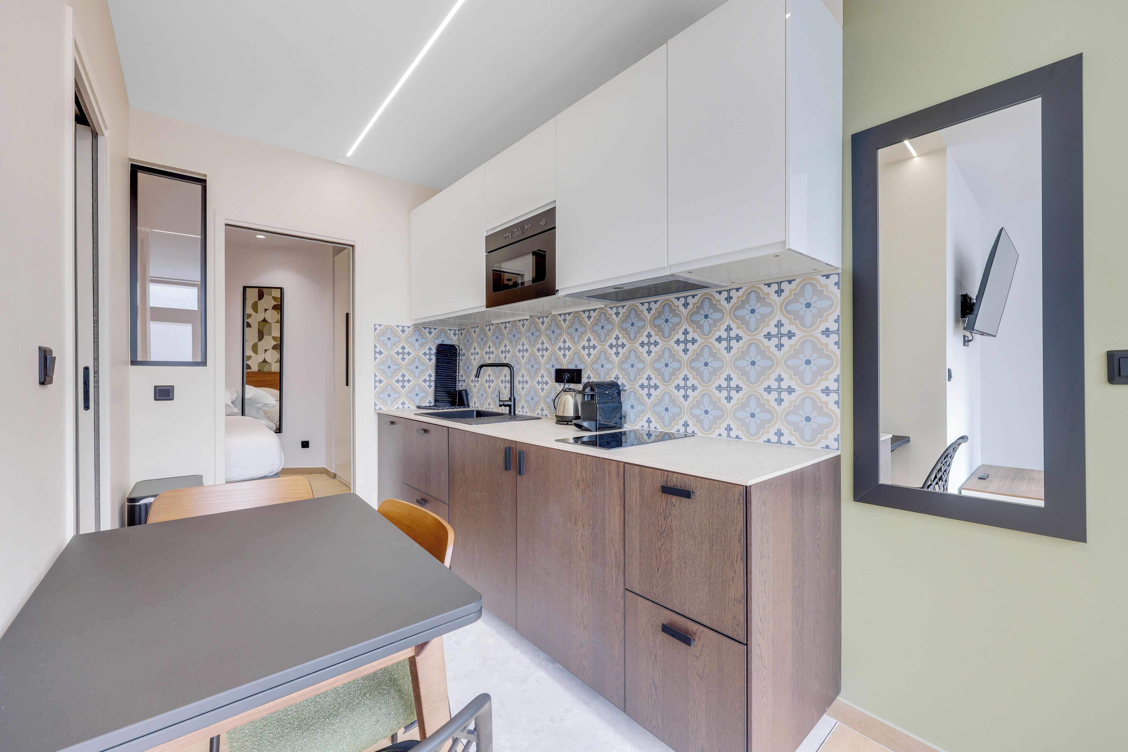 A compact kitchen with a dining area, a microwave, a coffee maker, and a large mirror.
