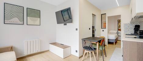 Um espaço moderno com área de jantar, televisão na parede e uma kitchenette.