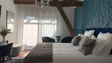 Een slaapkamer met een groot bed, een kroonluchter, een blauwe accentmuur en uitzicht op de omgeving.