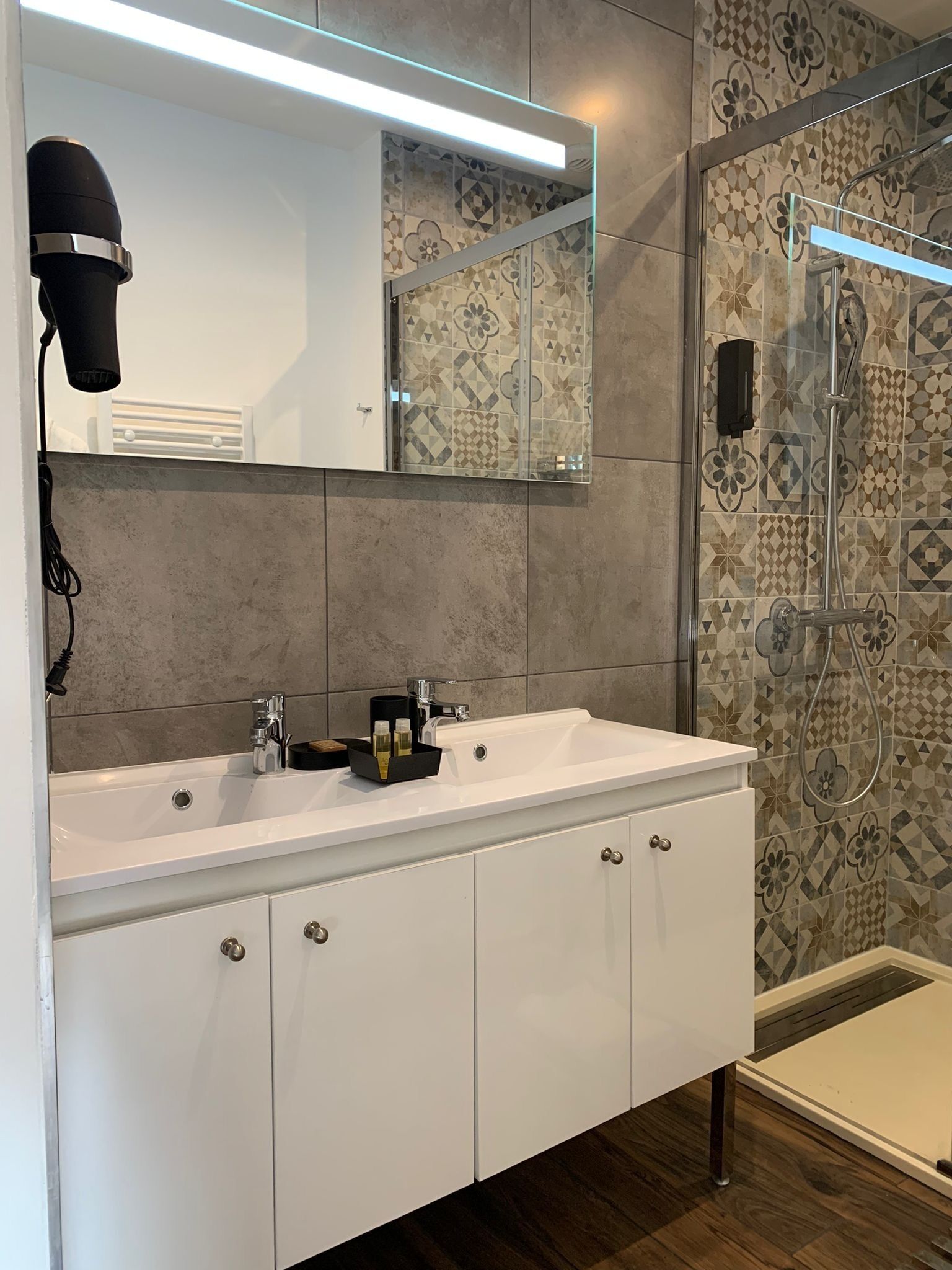 Casa de banho moderna com toucador branco, um espelho grande e zona de duche.