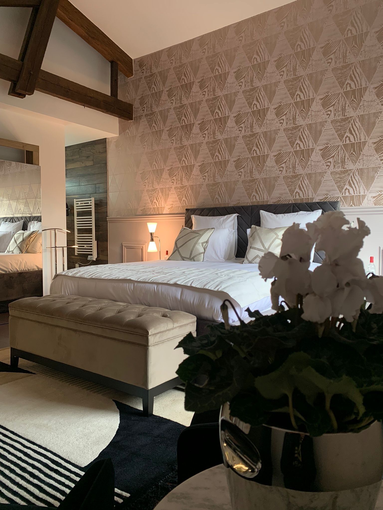 Un dormitorio con una cama grande, una mesita de noche, una silla y una planta en maceta.