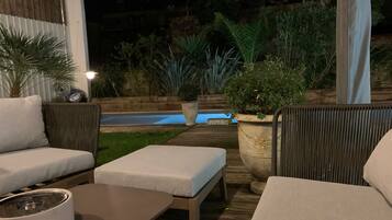 Eine Außenpatio-Terrasse mit Pool, Holzdeck und Sitzgelegenheiten.