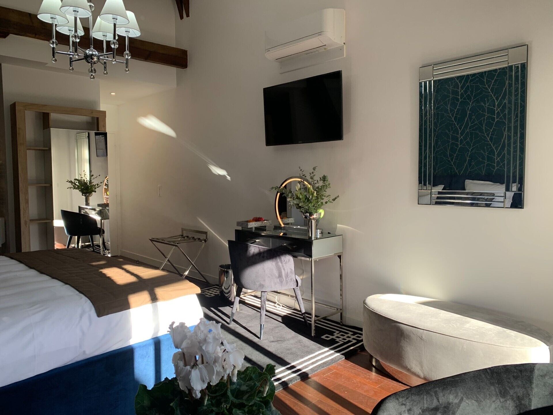A modern bedroom with a bed, desk, chair, and a TV on the wall.