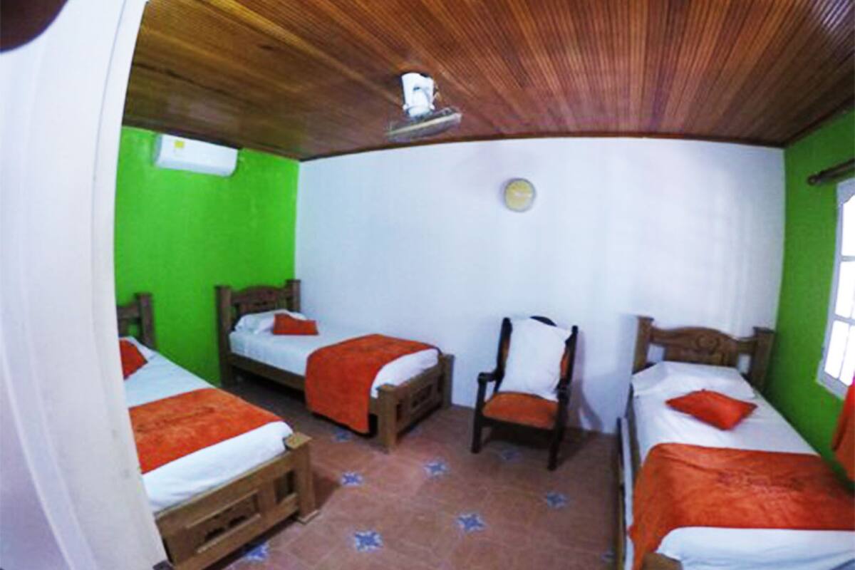A room with two beds, a chair, and a wooden ceiling.
