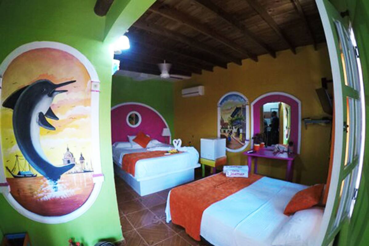 A room with a bed, a desk, and a wall with a dolphin mural.
