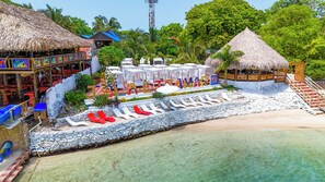 Privat strand, hvit sand, solsenger og parasoller