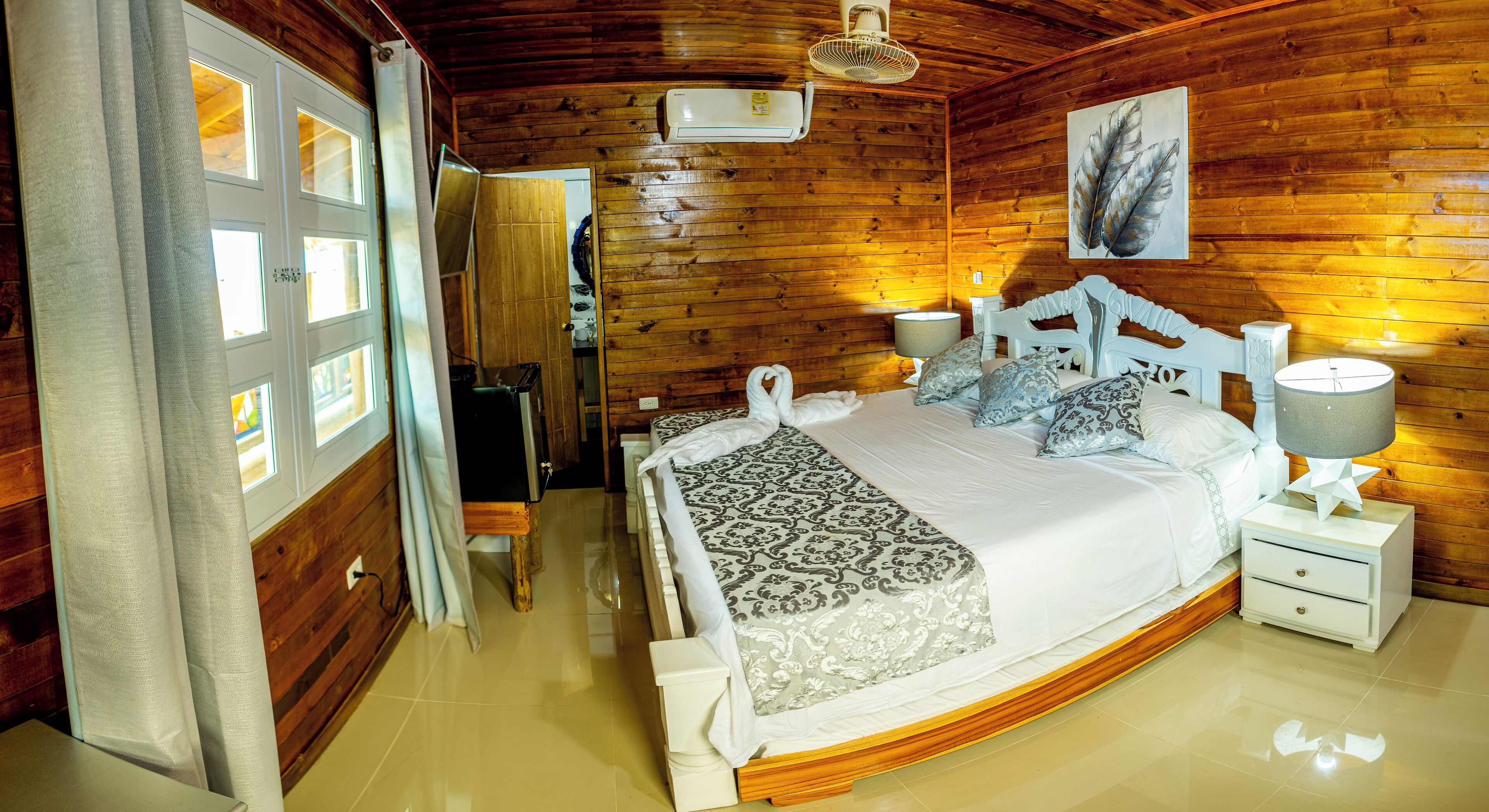 A wooden-paneled bedroom with a bed, bedside tables, and a ceiling fan.