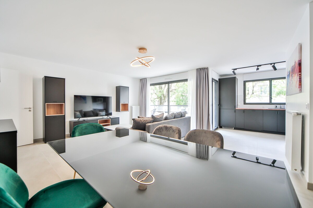 A modern living room with a large flat-screen TV, a dining table, and a sofa.
