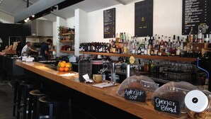 A bar area with a wooden counter, stools, and a menu board. - Fabulous 2BR close to the heart of East Fremantle - walk to the river (East Fremantle)