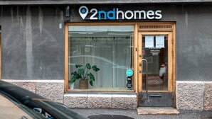 A storefront with a large glass window, a wooden door, and a sign reading "2ndhomes".
