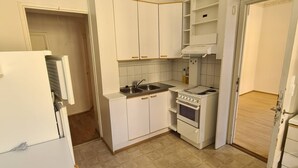 A compact kitchen with white cabinets, a stove, and a sink.