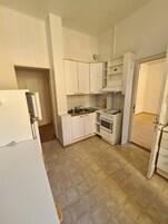 Una cocina compacta con armarios blancos, una estufa y un lavamanos.