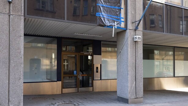 A building entrance with a glass door, a metal staircase, and a sign with the number 25.
