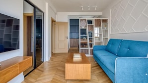 Ein modernes Wohnzimmer mit blauem Sofa, Couchtisch aus Holz und eingebauten Regalen.