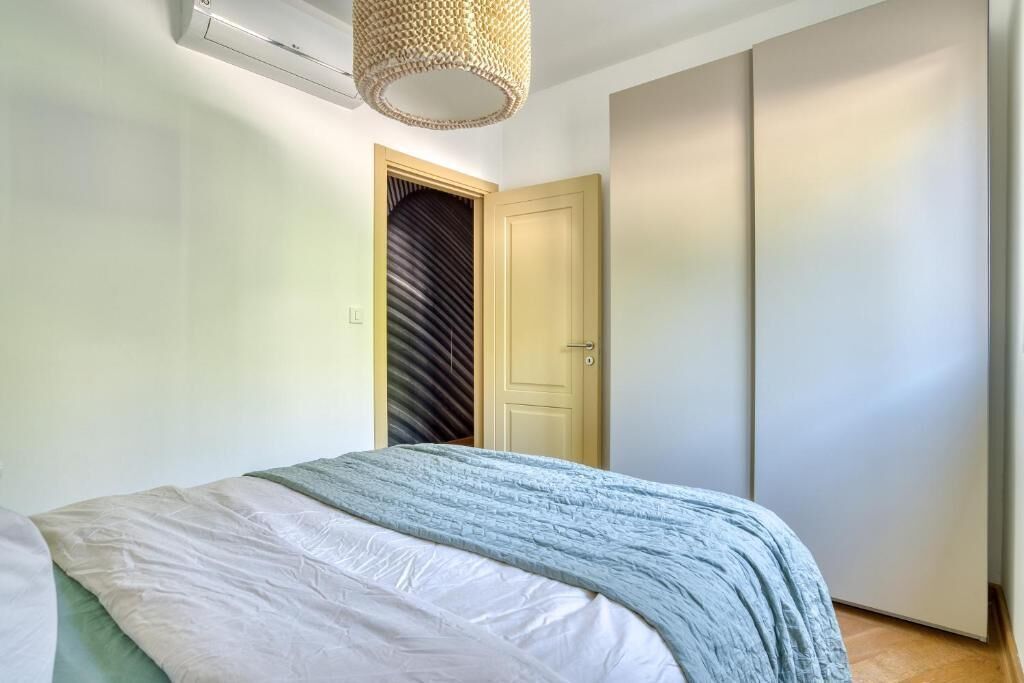 Un dormitorio con cama, una puerta y aire acondicionado instalado en la pared.