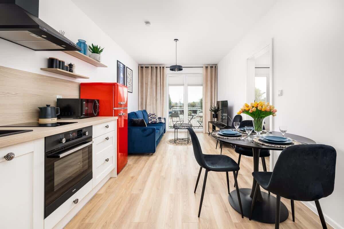 Eine moderne Küche mit Essbereich, einem roten Schrank und einem blauen Sofa.