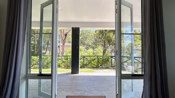 Habitación con un amplio ventanal corredizo que da a un espacio exterior con un banco de madera y vegetación.