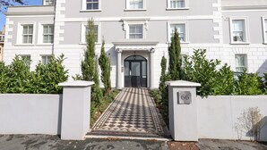 A two-story building with a symmetrical facade, a central entrance with a black door, and a tiled pathway leading to the entrance. - 3 Compass Point (Weymouth)
