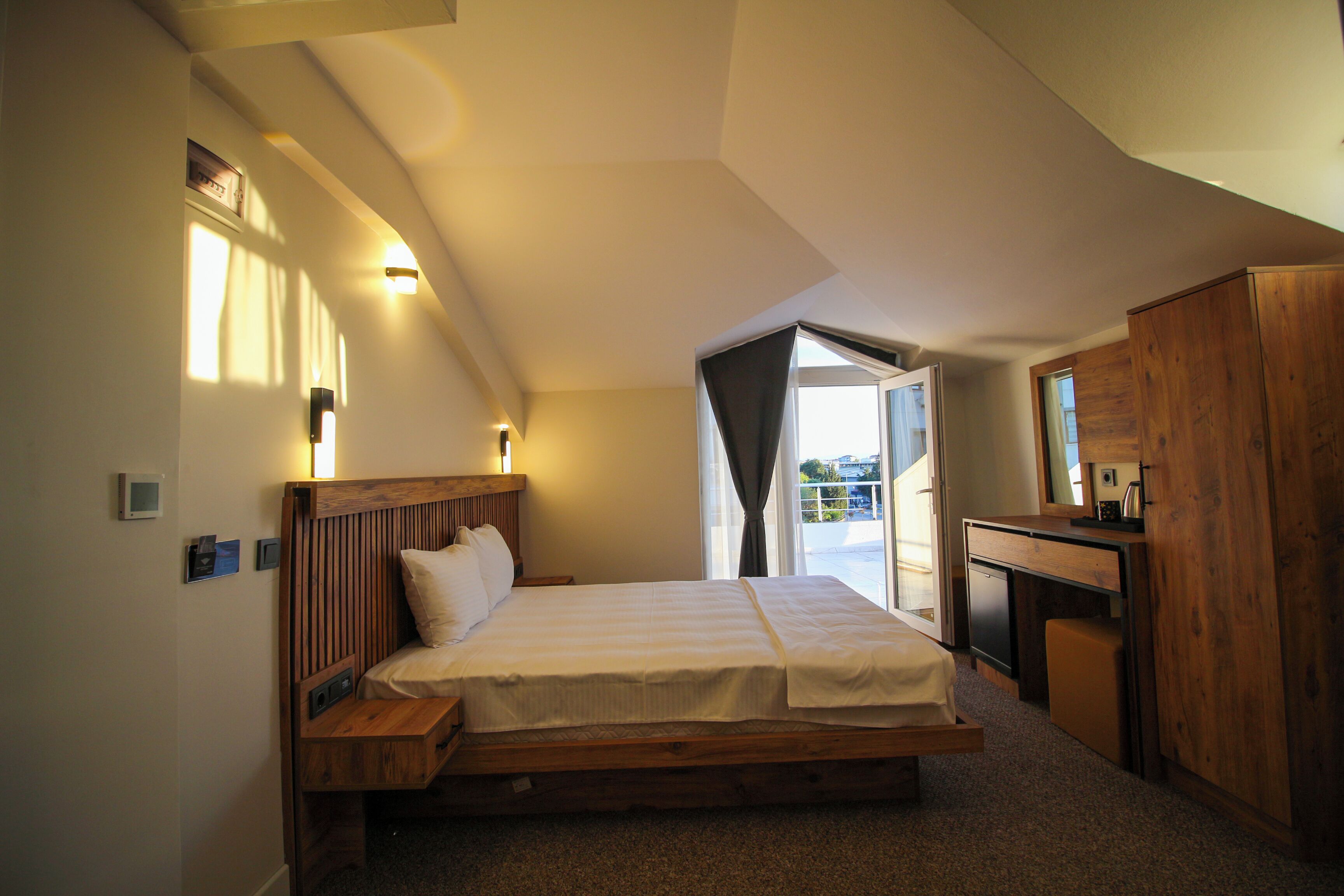 A bedroom with a wooden bed, a desk, and a wardrobe.