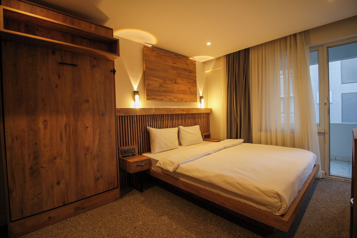 A hotel room with a large bed, wooden headboard, and a wooden wardrobe.