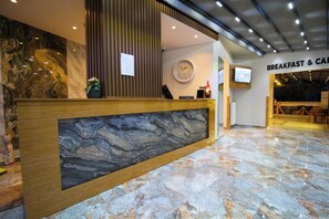 A hotel reception area with a marble counter, a clock, and a sign for breakfast and childcare services. - Luvira Hotel  (Istanbul)